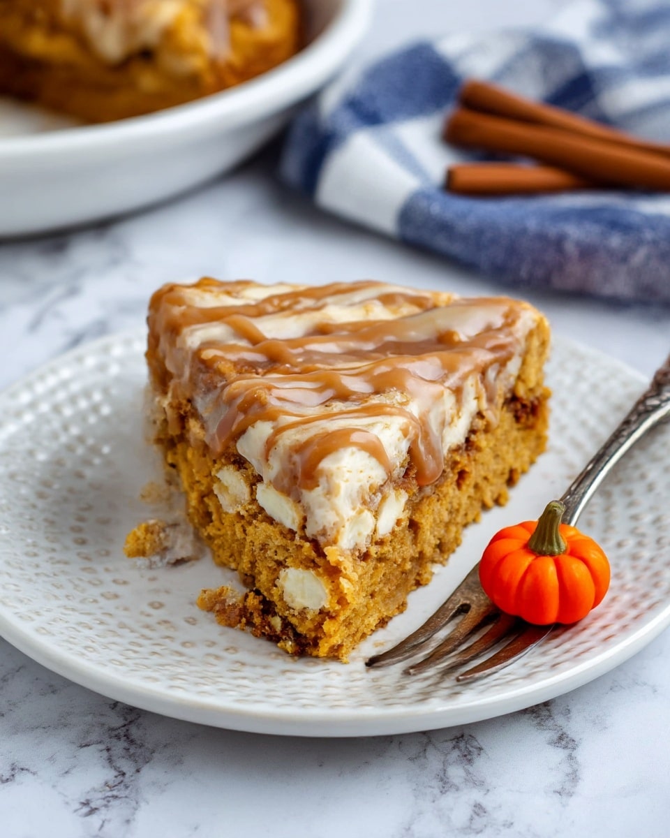A slice of pumpkin dessert sits on a white plate with a patterned edge. The bottom layer is crumbly and golden brown with visible soft chunks inside, followed by a creamy light layer with white bits. The top layer is a thick pumpkin cake with a smooth light brown drizzle sauce spread across it. A vintage fork lies to the right of the plate, next to a small bright orange pumpkin decoration. In the background, a cinnamon stick and a folded blue and white cloth rest on a white marbled surface. Photo taken with an iphone --ar 4:5 --v 7