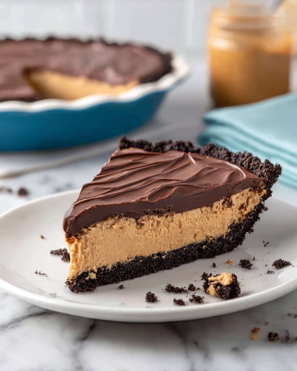 A slice of pie is shown on a white plate, featuring three distinct layers: the bottom layer is a dark, crumbly crust that looks like crushed chocolate cookies, the middle layer is a thick, light tan peanut butter filling with a smooth texture, and the top layer is a thick spread of dark chocolate ganache with soft, wavy swirls across its surface. Some crumbs are scattered on the plate around the slice. In the background, there is a whole pie in a blue pie dish and a jar of peanut butter, all set on a white marbled surface. photo taken with an iphone --ar 4:5 --v 7