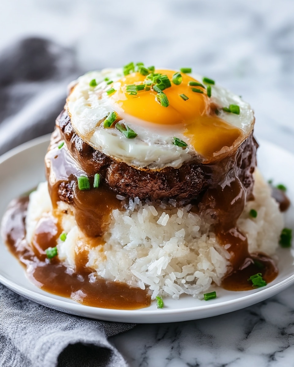 The dish shows a stack of three main layers on a white plate set on a white marbled surface with a folded gray cloth underneath. The bottom layer is a mound of fluffy white rice with visible grains. On top of the rice sits a thick, dark brown beef patty that looks juicy and charred on the edges. The patty is generously covered with glossy brown gravy that drips down the sides. The top layer is a sunny-side-up egg with a bright yellow yolk and white edges. Small pieces of green chopped chives are sprinkled on the egg and gravy, adding a fresh touch. Photo taken with an iphone --ar 4:5 --v 7