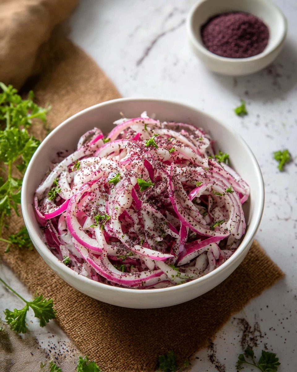 A white bowl filled with thinly sliced red onions mixed with small green parsley leaves, all lightly sprinkled with dark purple powder, creating a fresh and colorful texture. The onions show layers of white and vibrant pink, sitting on top of a layer of the same mixture, with visible seasoning throughout. The bowl is placed on a brown textured mat with some scattered parsley leaves nearby, and a small white bowl with more dark purple powder in the background. The whole scene rests on a surface with a white marbled texture. photo taken with an iphone --ar 4:5 --v 7