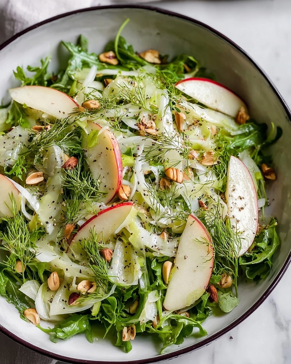 A fresh salad presented in a white bowl with a dark rim, layered with leafy green arugula as the base, topped with thin white and light green fennel slices, and sprinkled with bright green dill sprigs throughout. Red and green apple slices with crisp edges are evenly scattered on top, adding pops of color. Small chunks of light brown nuts are spread across the salad, enhancing the texture. The salad is lightly drizzled with a glossy dressing and sprinkled with black pepper on the top. The scene is set on a white marbled surface. photo taken with an iphone --ar 4:5 --v 7