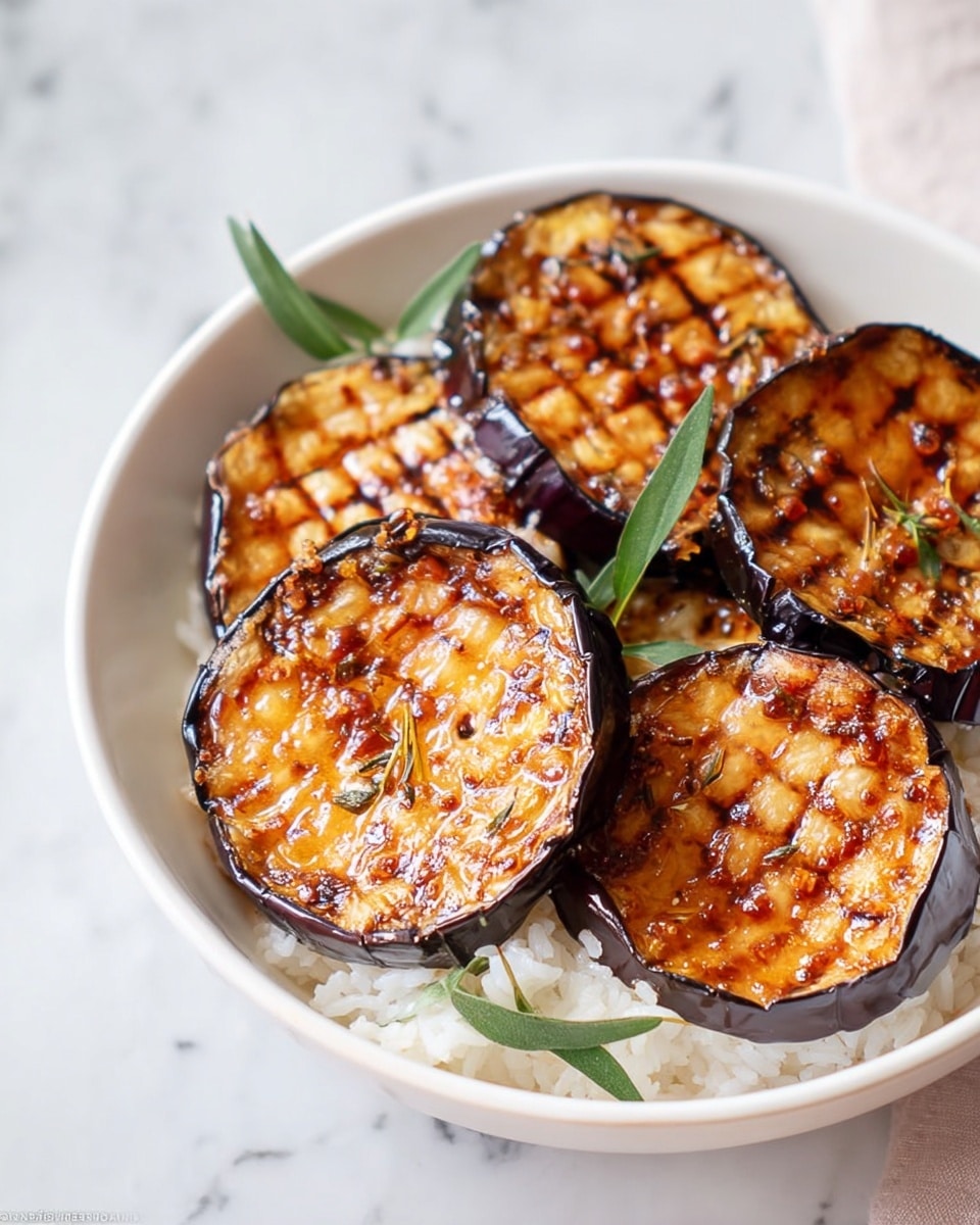 The image shows a white bowl with four thick slices of grilled eggplant placed on a bed of white rice as the first layer. Each eggplant slice is deep purple on the outside with a golden-brown grilled surface on top featuring a crisscross pattern. The grilled texture appears caramelized with small bits of seasoning and slight charring. Around the eggplant slices, thin green herb leaves are scattered for garnish. The bowl sits on a white marbled surface with a soft blurred background. photo taken with an iphone --ar 4:5 --v 7